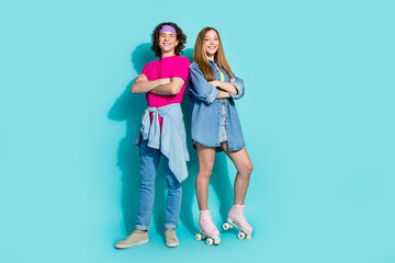 Full length photo of two happy teenagers spend time together folded arms wear roller skates and retro look isolated on cyan color background