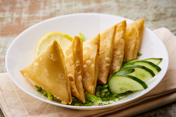 Deep Fried Sambosa Cheese samosa triangle wrap with lime and cucumber served in dish isolated on...
