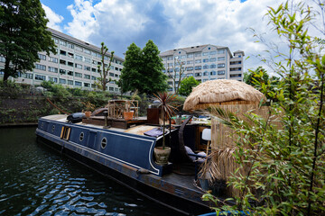 London - 29 05 2022: Lisson Grove Pier with moored houseboat, with bamboo patio and umbrella.