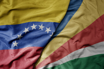 Fototapeta premium big waving national colorful flag of seychelles and national flag of venezuela . macro