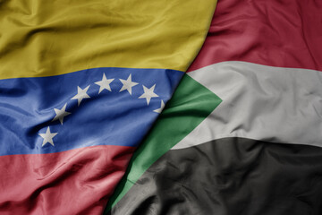 big waving national colorful flag of sudan and national flag of venezuela . macro