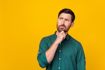 Photo of distrustful man with brunet hair dressed dotted shirt look at proposition empty space isolated on yellow color background