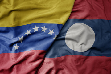 big waving national colorful flag of laos and national flag of venezuela . macro