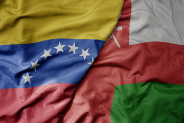 Fototapeta premium big waving national colorful flag of oman and national flag of venezuela . macro