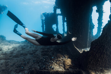 Attractive woman freediver swims underwater among the ruins of a ship. Freediving at wreck ship