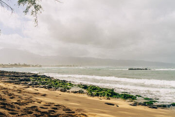 beautiful beach with black rocks on a stormy day on oahu in hawaii