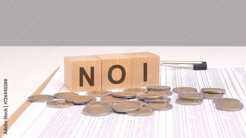 Poster text noi on wooden cubes with coins. noi for net operating income in real estate, signifying the pro