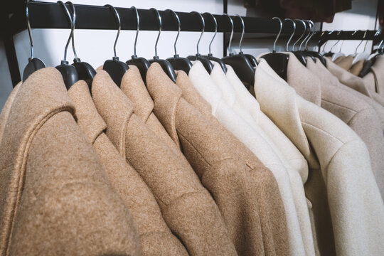 Women's coats of natural beige sand and brown color on hanger in store