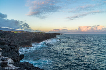 full moon during sunset over the cliffs of the volcanos on the coast of the pacific on big island in hawaii