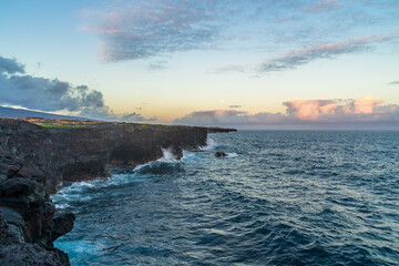 full moon during sunset over the cliffs of the volcanos on the coast of the pacific on big island in hawaii