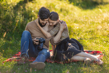 Fototapeta premium young couple relaxing in nature and looking at photos on a camera