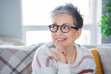 Photo of pretty thoughtful woman dressed striped sweater eyewear having rest couch indoors house home room