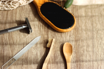 Crochet bag, wooden hairbursh, face roller, reusable razor, glass nail file, wooden toothbrush and wooden spoon on wooden background. Various zero waste products. Selective focus.