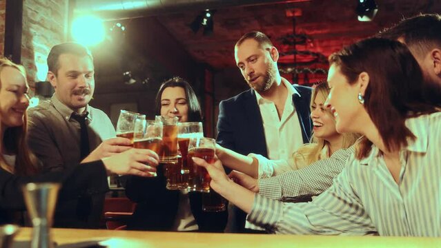 Celebrating successful project. Colleagues meeting at pub after work, greeting each other with good work, drinking lager beer, clinking glasses. Concept of leisure time, fun and joy, youth, enjoyment