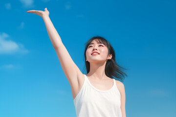 Cheerful Asian woman reaching towards the blue sky