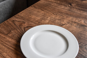 Ceramic white flat plate for food on wooden table top view