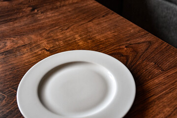 Ceramic white flat plate for food on wooden table top view