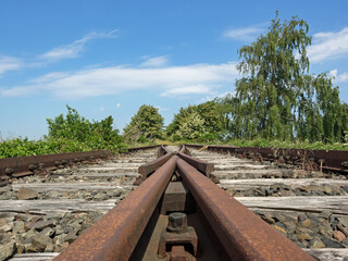 Verrostete Gleise einer stillgelegten Bahnstrecke führen ins Nirgendwo - 726461820