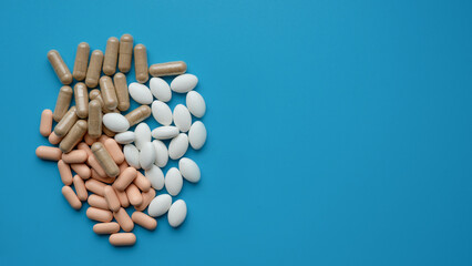 Pills of different colors and shapes on a blue background.