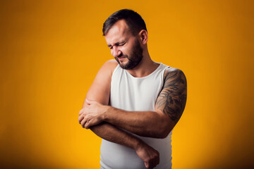 Man suffering from elbow pain. Tattoo on shoulder. People, healthcare and medicine concept