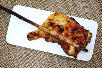 grilled chicken with bamboo sticks on mat