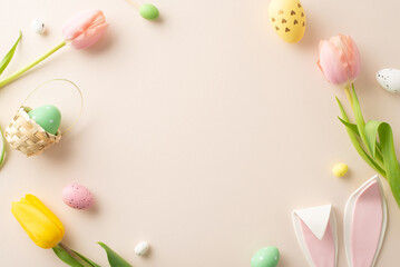 Fototapeta na wymiar Springtime Joy Composition: Lively eggs, cute bunny ears, and tulips on a pastel beige background. Top view photo with an open frame ready for your text or promotional message