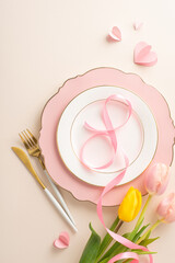 Chic Women's Dinner Display: top view vertical photo of a sophisticated plate with an 8-shaped ribbon, flatware, alluring tulips, and hearts on a pastel beige canvas, blank space for script