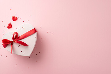 Supreme female celebration concept. Overhead perspective of snazzy heart-shaped package, trimmings, and glitter strewn on a pastel pink stage, blank area for text or advert