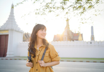 Traveler asian woman in her 30s stands bathed in the golden glow of sunset, embracing the freedom...