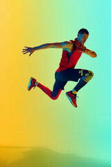 Fototapeta na wymiar Full-length image of muscular athletic man in sportswear training against gradient blue yellow background in neon light. Concept of active and healthy lifestyle, sport, fitness, endurance