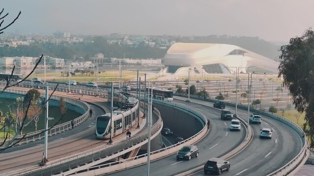a tram is passing through a bridge in front of the Grand Theatre with a busy traffic