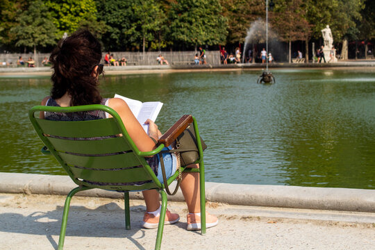 Woman reading a book next to the fountain in the garden of the royal palace, Paris, France