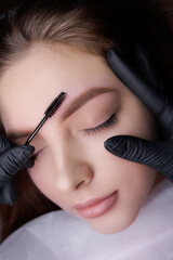 Macro photo after the procedure of permanent eyebrow makeup master combing the eyebrows with a...
