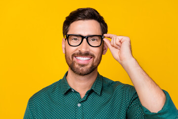 Photo of cheerful clever man with stylish haircut dressed dotted shirt holding eyewear smiling isolated on yellow color background - obrazy, fototapety, plakaty