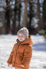 Portrait of two year old boy standing in fresh snow in winter playing outdoors