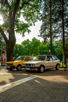 Perfect condition Volkswagen Cabrio (based on Golf 1) in white color and YUGO Koral (Zastava Koral, Yugo 45, 55) in yellow color are parked in Subotica, Serbia 21.06.2023 - vertical image.