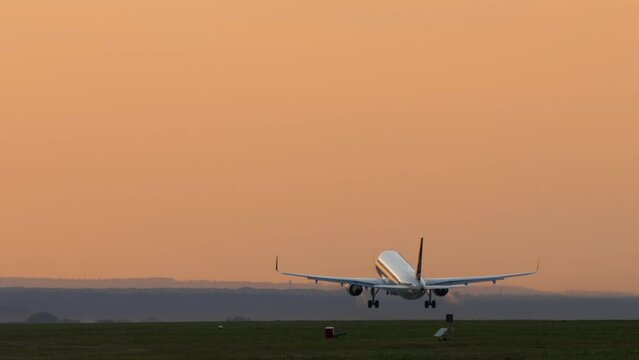 Cinematic footage of a jet plane taking off at sunset, dawn in backlight. Tourism and travel concept, modern aviation