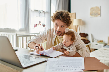 man holding in arms his infant son while working remotely on laptop from home, work-life balance - obrazy, fototapety, plakaty