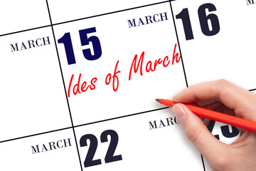 March 15. Hand writing text Ides of March on calendar date. Save the date.