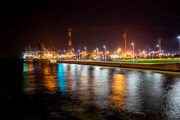 Fototapeta na wymiar An engaging night scene unfolds at the Port of Antwerp, where the artificial lights create a vibrant tapestry against the dark sky. The reflection of the lights on the water adds a layer of depth and
