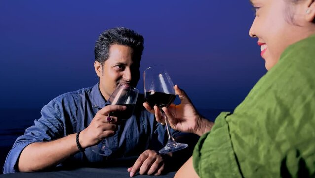 drunk man sitting on the beach with his wife drinking red wine consuming alcohol desperately young couple