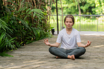 Fototapeta premium Little girl child doing yoga exercise relax in the park. stretching on the grass summer day