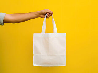 Hand Holding Blank White Tote Bag Against Yellow Background - Generative AI