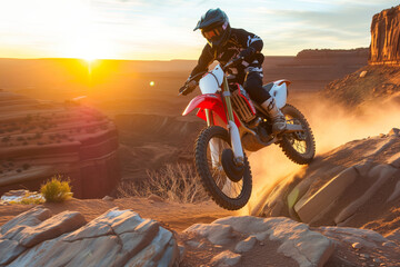 dirt biker taking a rocky terrain jump at sunset