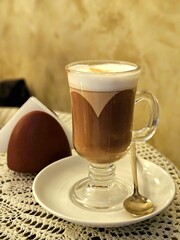 A cup of coffee (latte macchiato) standing on the table in cafe. Transparent glass with latte in a cafe