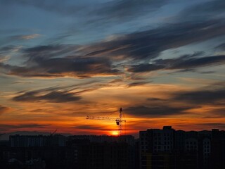 Beautiful sunset over the city. Colored clouds at sunset. Construction site at sunset. Sunset over city