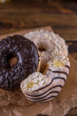 Several donuts on baking paper on a wooden background.