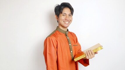 Asian Muslim man smiling is holding al-quran