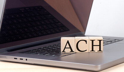 ACH word on wooden block on laptop, business concept