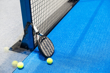 Paddle tennis racket, ball and net on the court